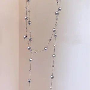 Detailed view of a retro long grey pearl layered necklace, perfect as a sweater chain.