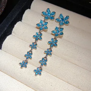 Close-up detail of elegant long tassel earrings featuring blue zircon flower patterns
