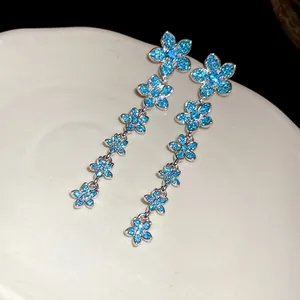 Exquisite close-up of long tassel earrings featuring sparkling blue zircon flower motifs