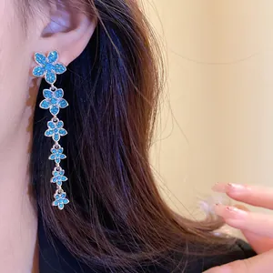 Close-up of elegant silver-toned tassel earrings with blue zircon flower drops.