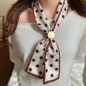 Primo piano della collana sciarpa vintage a pois con elegante fibbia dorata.