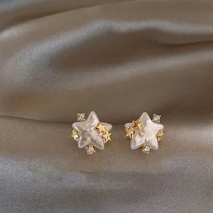 Close-up of star-shaped pearl stud earrings with gold accents and sparkling zircons