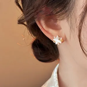 Detail of elegant star-shaped stud earring with pearls and zircon on model's ear