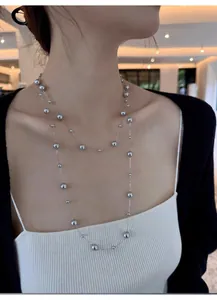 Detail view of double-layered long silver bead necklace on model for fashion look.