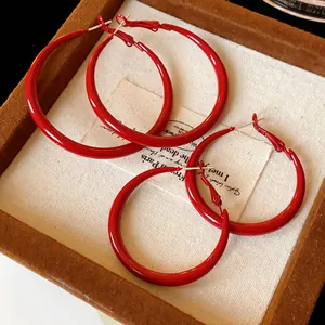 Close-up detail of vintage style red lacquer circular hoop earrings in a velvet display box