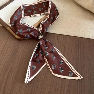 Dettaglio di collana a foulard in seta marrone con motivo paisley e anello in metallo