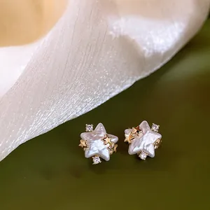 Detailed close-up of elegant star-shaped pearl stud earrings with gold accents and zirconia