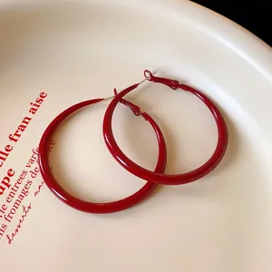 Close-up of vibrant red spray-painted hoop earrings in a vintage minimalist design
