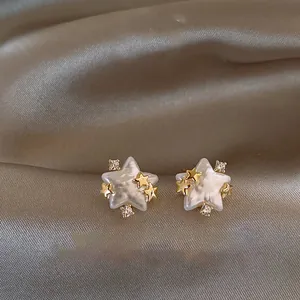 Close-up detail of elegant gold-plated zircon star stud earrings with pearl finish