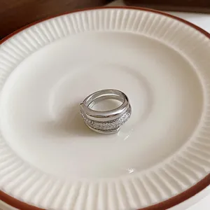 Detailed macro shot of a silver layered zircon open ring on a white saucer