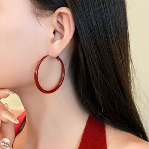 Detailed view of elegant retro red painted large hoop earrings worn on a model's ear