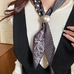 Primo piano della collana a sciarpa in tessuto retrò con pois, paisley e fibbia in metallo.