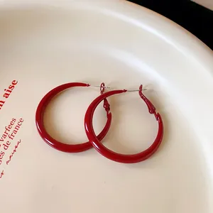 Macro detail view of glossy red vintage style spray-painted hoop earrings for women