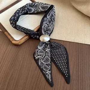 Dettaglio della collana foulard nera con eleganti motivi paisley e pois bianchi