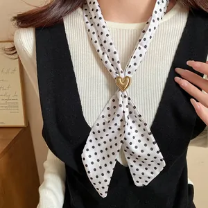 Primo piano di una collana sciarpa retrò a pois con una elegante chiusura a cuore dorato.
