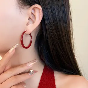 Close-up of a model wearing exaggerated burgundy spray-painted hoop earrings