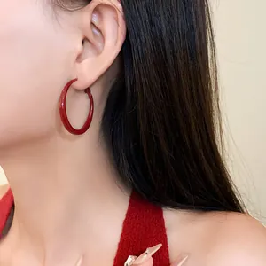 Detailed view of retro minimalist red sprayed paint round hoop earrings worn on ear