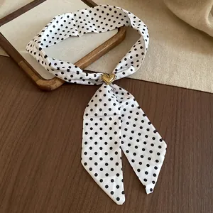 Dettaglio della collana a foulard in tessuto a pois bianchi con fibbia a cuore d'oro