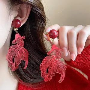 Detail showing red koi fish earrings with an intricate hollow metal design for New Year