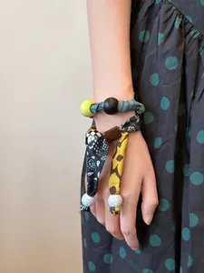 Macro view of handmade cloth necklace with varied fabric patterns and colorful beads on wrist.
