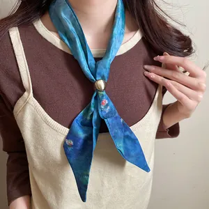 Dettaglio di una collana sciarpa di seta vintage con motivo floreale blu e cursore dorato.
