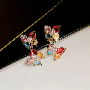 Detailed view of butterfly earrings with vibrant colorful zircon stones on a dual-tone backdrop
