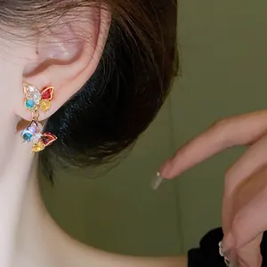 Close-up of colorful zircon butterfly earrings worn by a model in a lifestyle setting.
