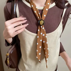 Primo piano di una collana a sciarpa vintage a pois marroni con ciondolo in legno
