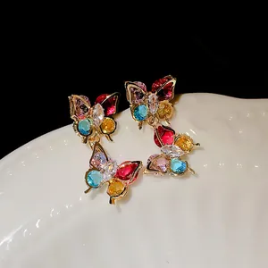 Detailed macro view of vibrant colorful zircon butterfly drop earrings with gold plating.