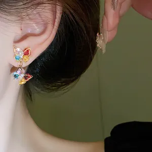 Close-up of colorful zircon butterfly earring worn on ear showing vibrant stones