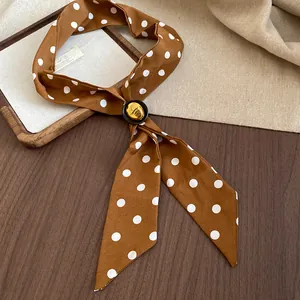Dettaglio di una collana a foulard in tessuto a pois marroni vintage su legno.