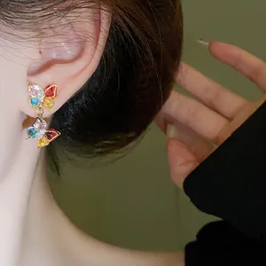 Close-up of elegant butterfly earrings with vibrant colorful zircons on a model's ear