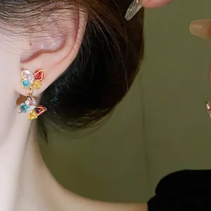 Detailed close-up showing colorful zircon butterfly drop earrings worn on a model's ear