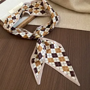 Dettaglio di un foulard in seta a rombi con un elegante fermaglio ad anello dorato