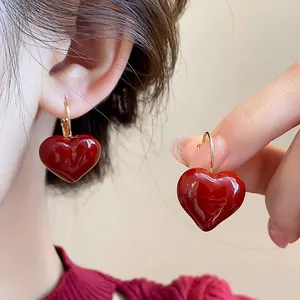 Detailed close-up view of vibrant red heart-shaped earrings with gold hooks for women