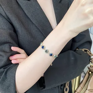 Close-up of elegant gold plated bracelet with sparkling blue and grey crystals on wrist.