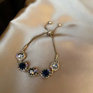 Elegant gold plated bracelet with sparkling blue and white crystals on silk background
