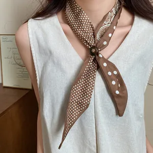 Primo piano di una collana a foulard in seta vintage marrone a pois con perla in legno