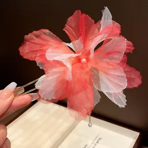 Close-up of red chiffon flower hair pin with pearl tassel for retro updo styling