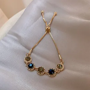 Macro view of gold-plated adjustable bracelet with blue and olive green stones