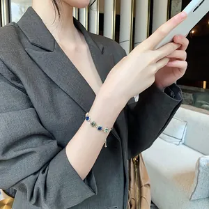 Close-up of a minimalist gold-plated bracelet with blue and green crystals on a wrist