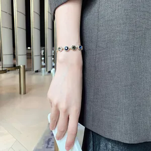 Close-up view of an elegant gold-plated bracelet featuring blue and grey crystals on a wrist