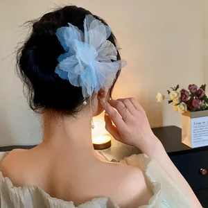 Back view of a model wearing a light blue chiffon flower hairpin with pearl tassels.