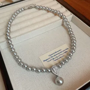 Detail view of a gray pearl necklace with a sparkling zircon teardrop pendant