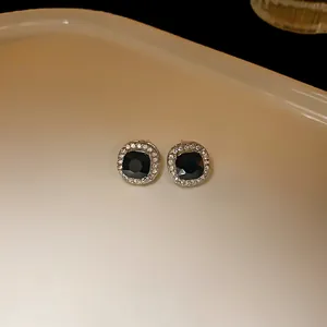 Close-up of elegant black square stud earrings with shimmering rhinestone halo