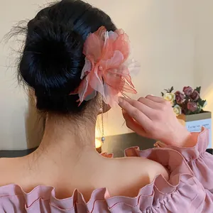 Detailed view of a large chiffon flower hair pin featuring a long pearl tassel on a bun.