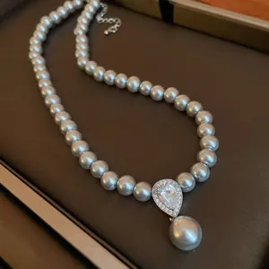 Detail of elegant grey pearl necklace with a zircon teardrop pendant in retro style.