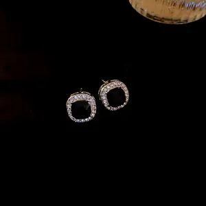 Elegant square black stud earrings with sparkling rhinestone halo on black background
