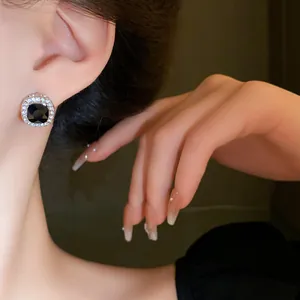 Close-up detail of elegant square black stone earrings with sparkling diamond halo accents