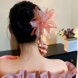 Back view of a large chiffon flower hairpin with pearl tassel detail shown on a model